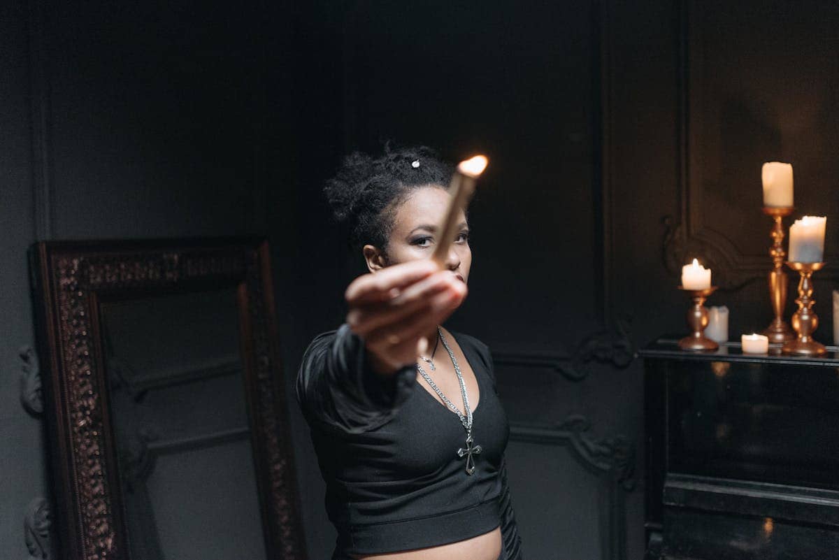 Mysterious woman holding a burning candle in a dark room for black mirror scrying ritual setup