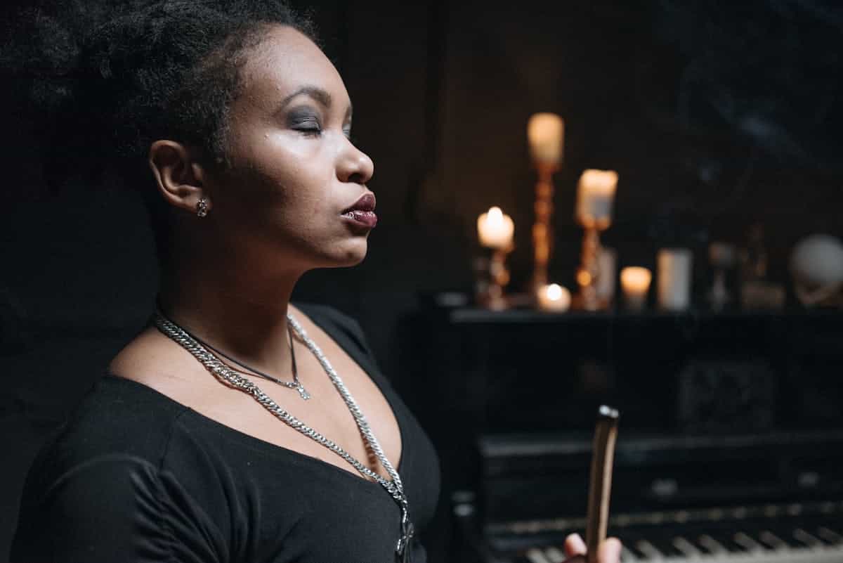 A woman meditates in a candlelit room with a mystical atmosphere, representing the meditative trance state used when working with a black mirror for spiritual vision