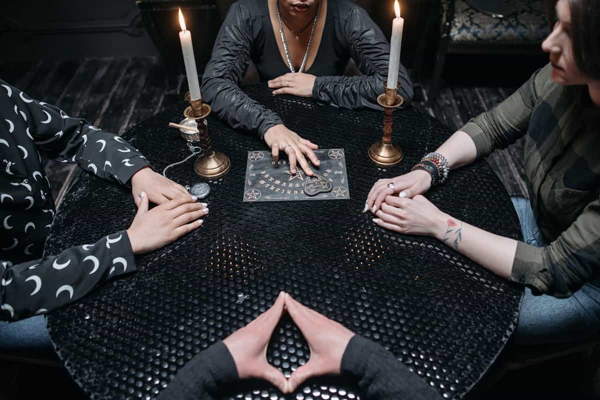 A group of adults engaging in a mysterious seance with Ouija board by candlelight in a dimly lit room