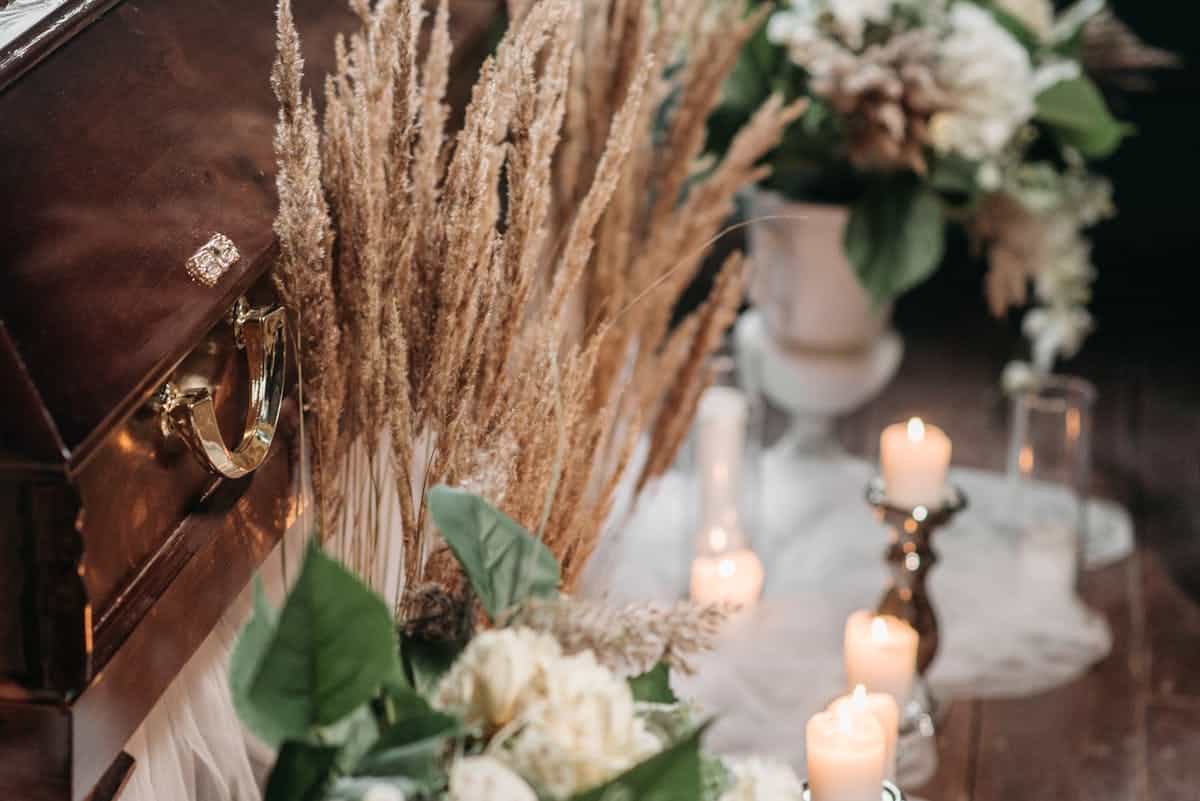 An elegant funeral setting featuring a wooden coffin surrounded by flowers and lit candles