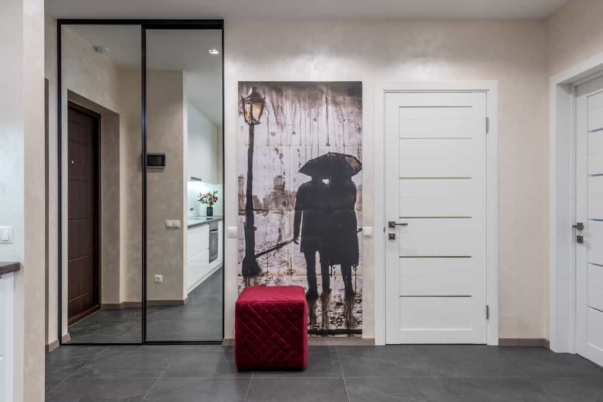 Wardrobe with mirrored doors and a red pouf in a bright room showing how a mirror for a wardrobe reflects light