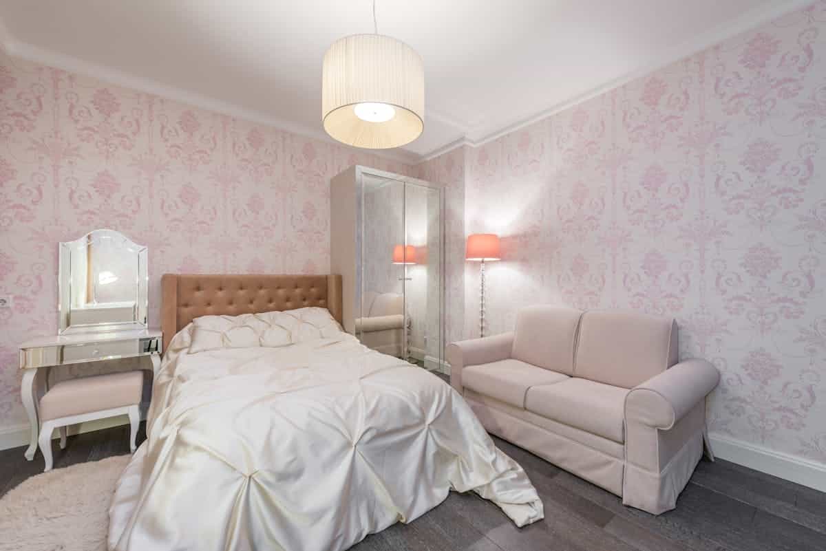 Bedroom with soft pink walls illustrating feng shui bedroom colors for love and romance Spacious contemporary bedroom with soft pink walls and white linen, illustrating feng shui colors for romance