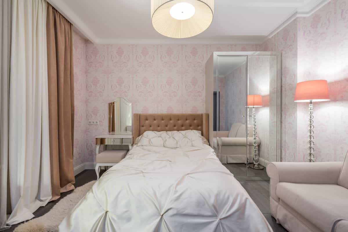 Bedroom with glowing bedside lamps positioned next to a wall mirror showing how mirrors over nightstands reflect light