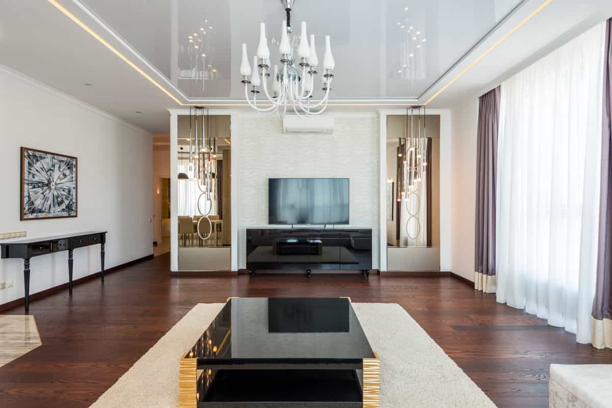 Stylish living room illustrating why a mirrored accent wall adds light and space Stylish living room with a chandelier and modern decor, illustrating why a mirrored accent wall works