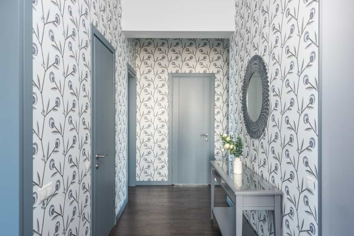 Hallway console table with a decorative mirror illustrating entryway mirror styles and shapes Hallway with floral wallpaper, a console table, and a decorative mirror showing entryway mirror styles