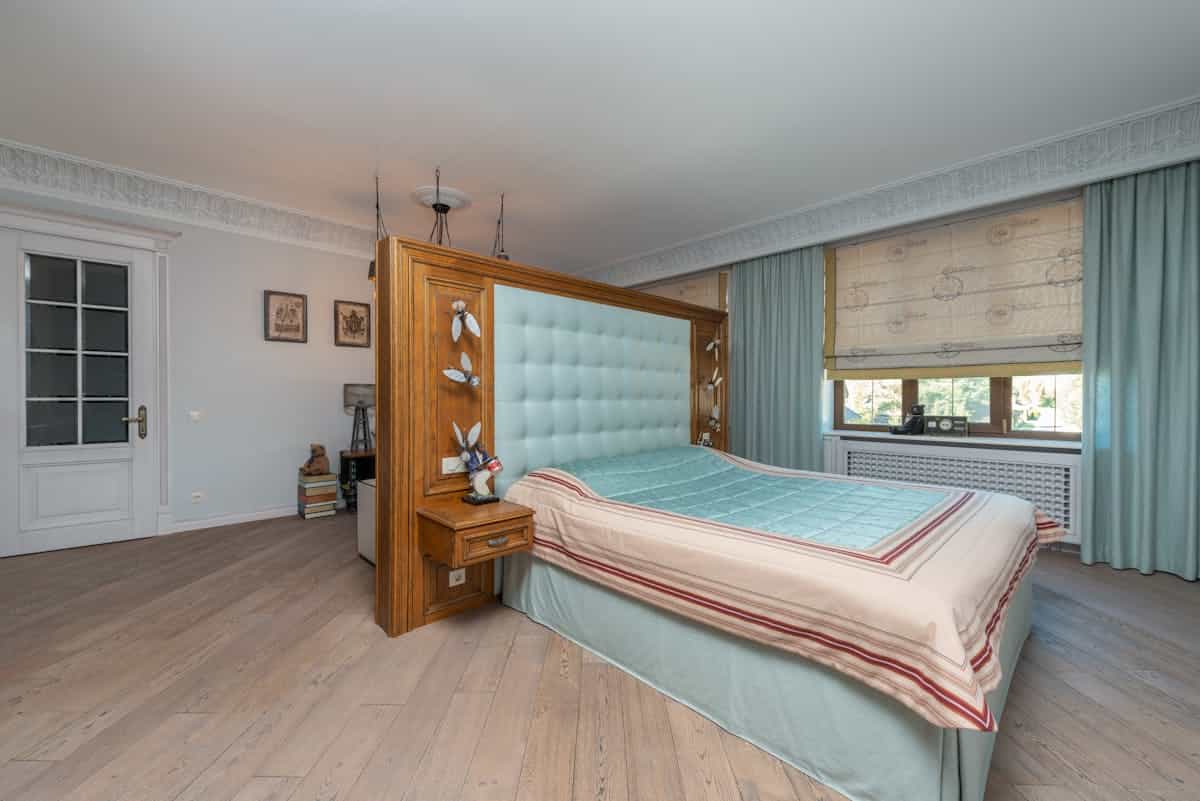 Stylish bedroom with a solid wooden headboard and soft pastel decor, illustrating the main feng shui fix for a bed under a window