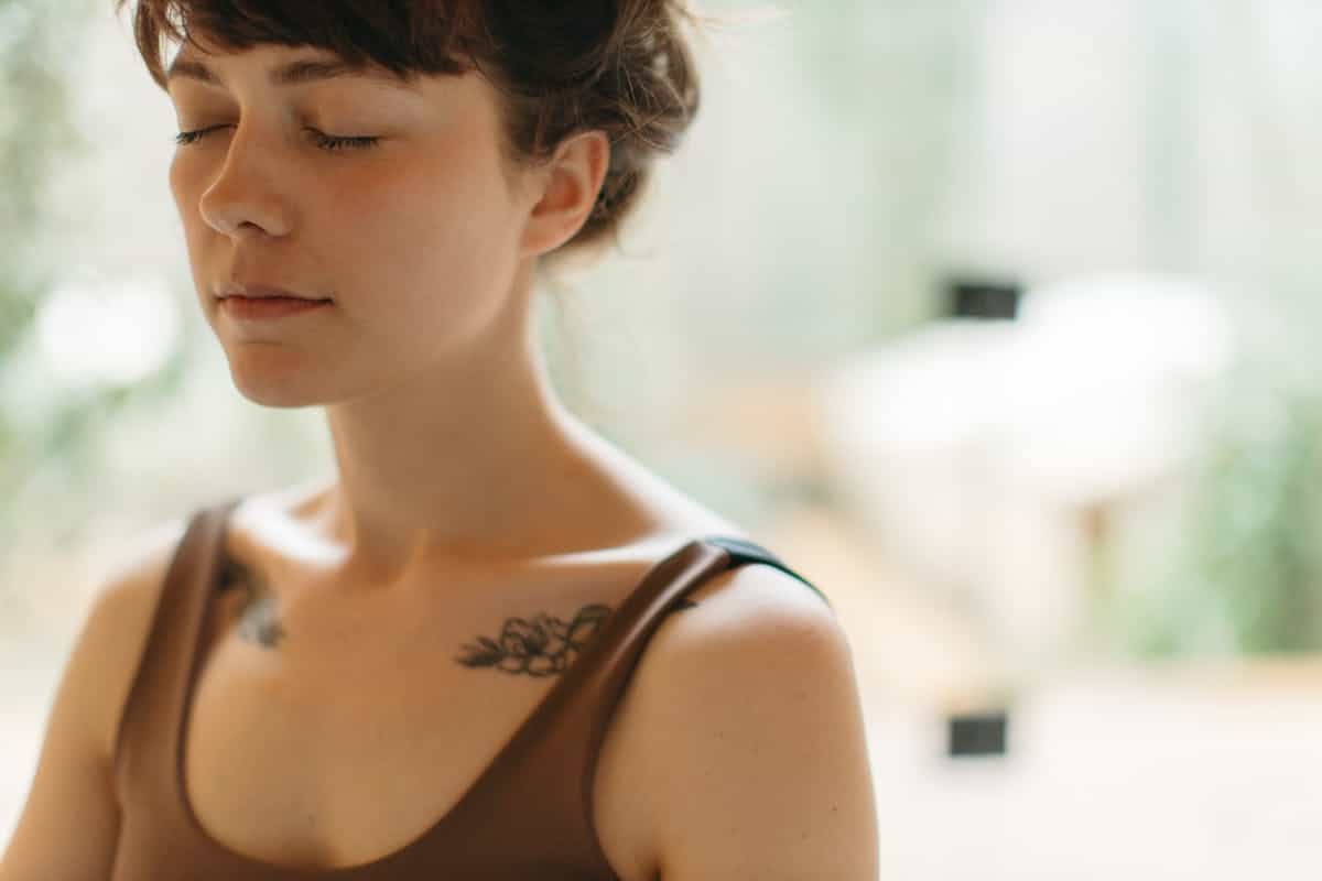 Woman meditating with closed eyes suggesting the inner stillness that makes the talking mirror dream's message accessible in waking life A woman with closed eyes meditates in a calm indoor setting evoking the quiet inner attention required to hear what a talking mirror dream is actually communicating