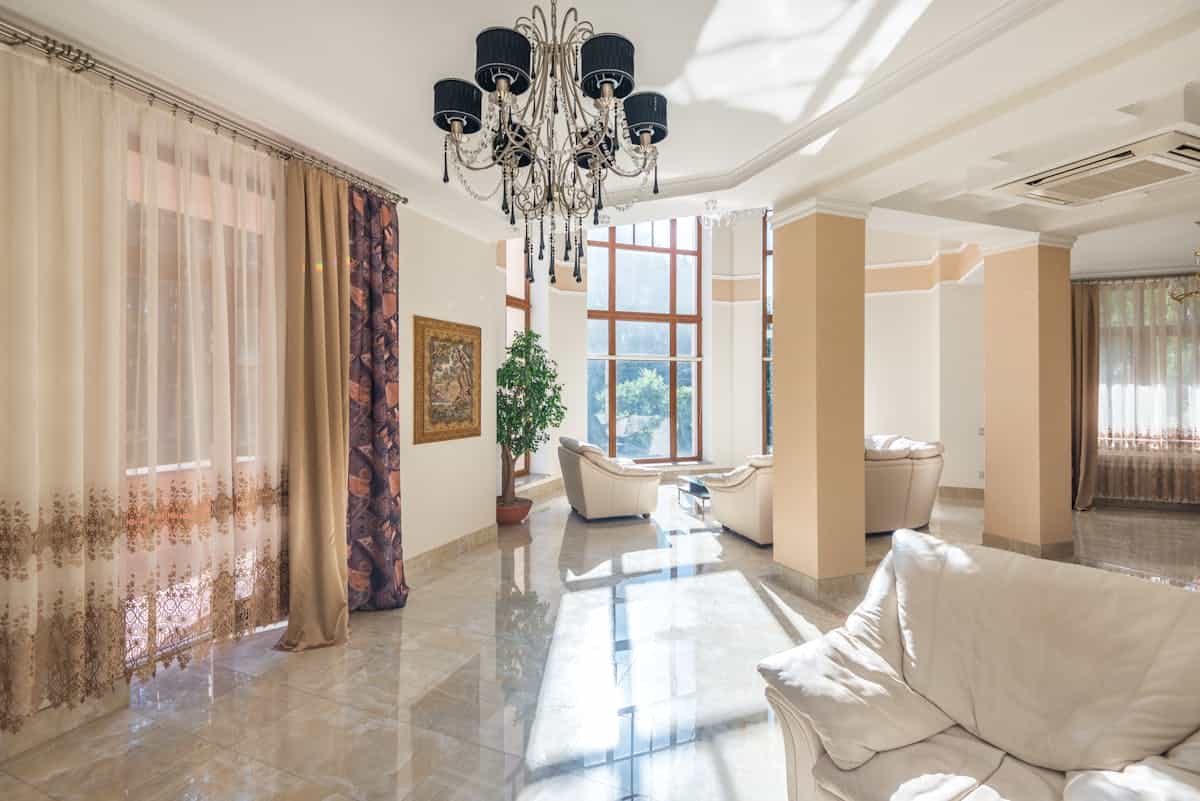 Bright spacious living room with chandelier large windows and soft seating Mediterranean elegance