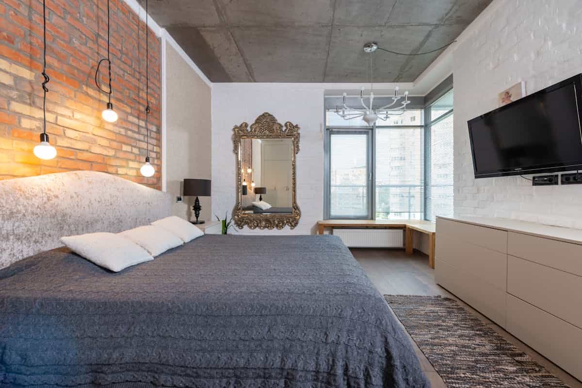 Large mirror hung above a bed showing how high a mirror should go above a headboard Large mirror on the wall above a king-size bed showing how high a mirror should go above a bed