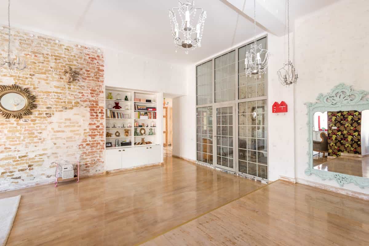 Bright room with multiple mirrored frames on a brick wall, illustrating a mirror gallery cluster