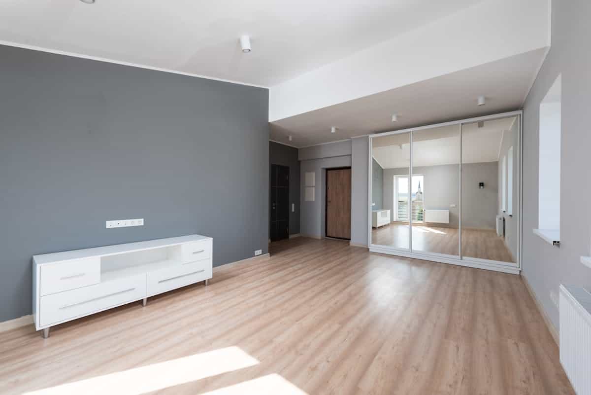 Spacious minimalist room with wooden flooring and a tall full length mirror, illustrating full length mirror sizing