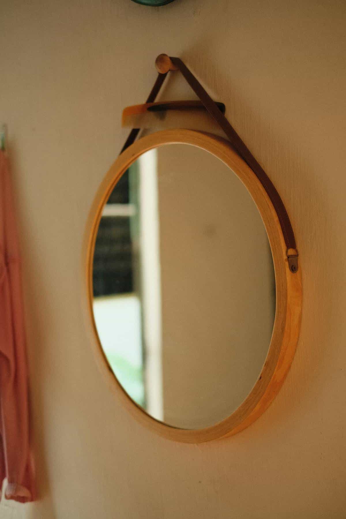 Wooden framed rectangular wall mirror in simple bright interior near window