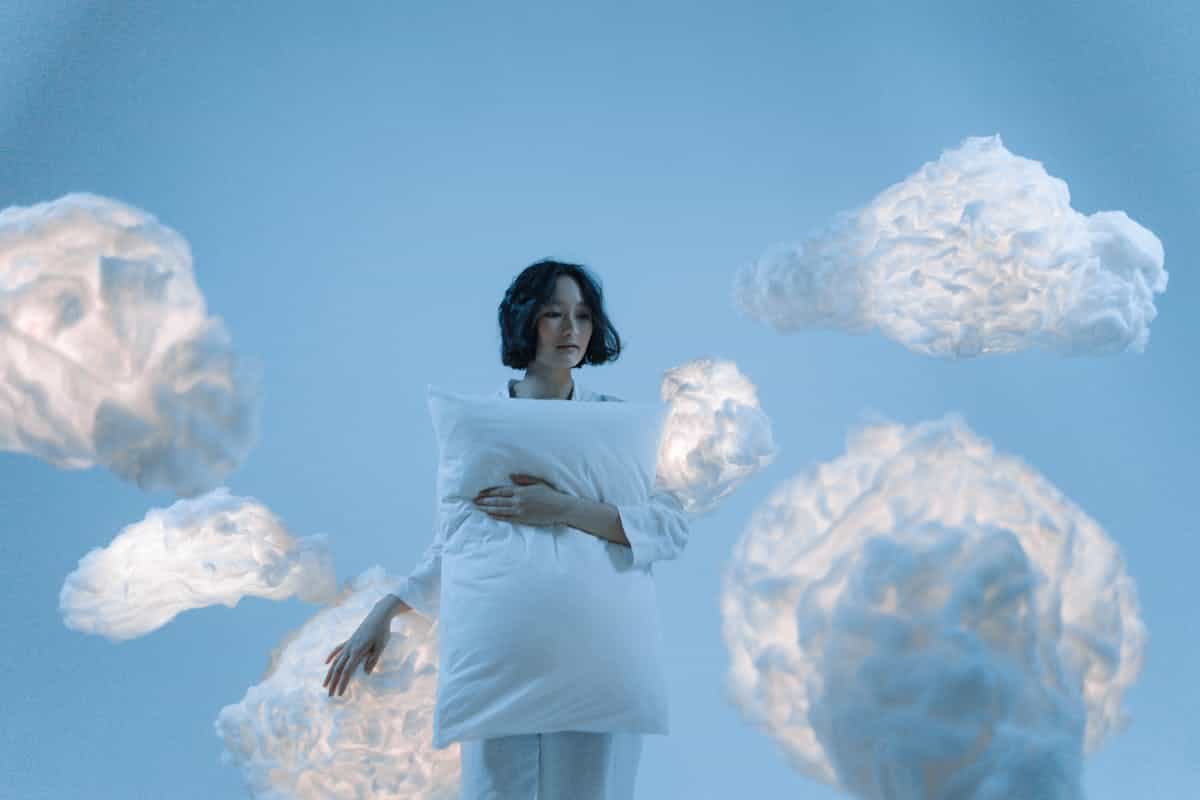 A serene dreamlike portrait of a woman holding soft clouds in a blue atmosphere representing the REM sleep neuroscience behind why mirror dreams generate specific faces