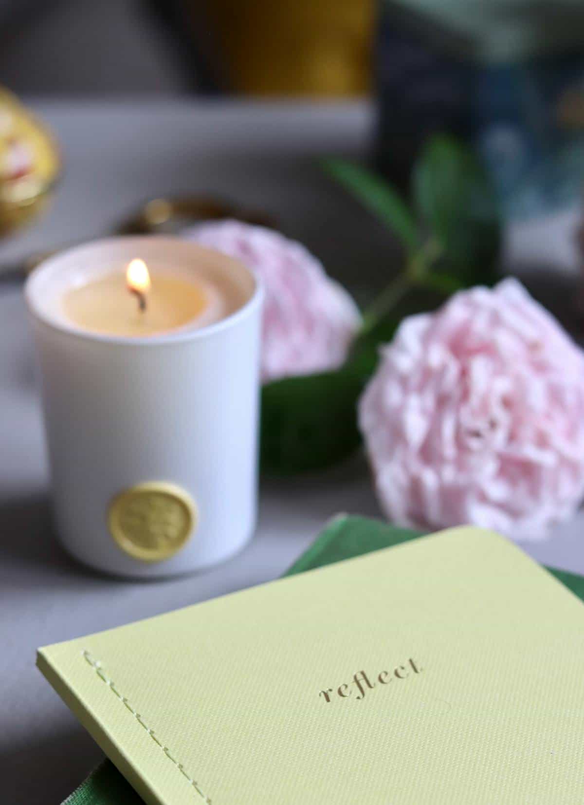 Candle notebook still life for journaling broken mirror dreams and emotional processing Lit candle with flowers and reflective notebook suggesting journaling after spiritual dreams