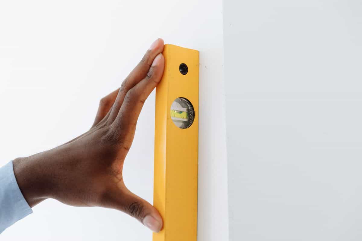 Using a spirit level on a wall to hang a bedroom mirror straight and secure Hand using a spirit level against a wall to hang a mirror straight and at the right height