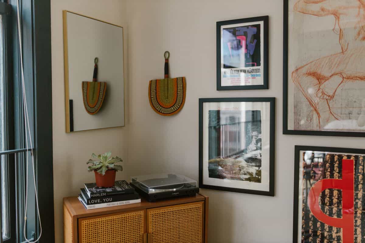Cozy interior with framed art, a wood-framed mirror, and a small plant on a wooden cabinet, illustrating why wood mirror frames work