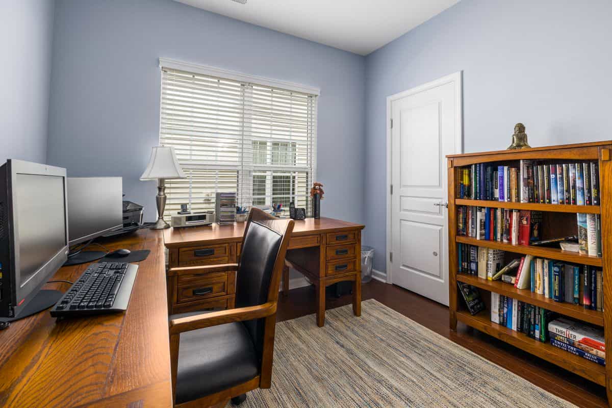 Bright home office with a wooden desk, chair and bookshelves, illustrating a feng shui home office setup.