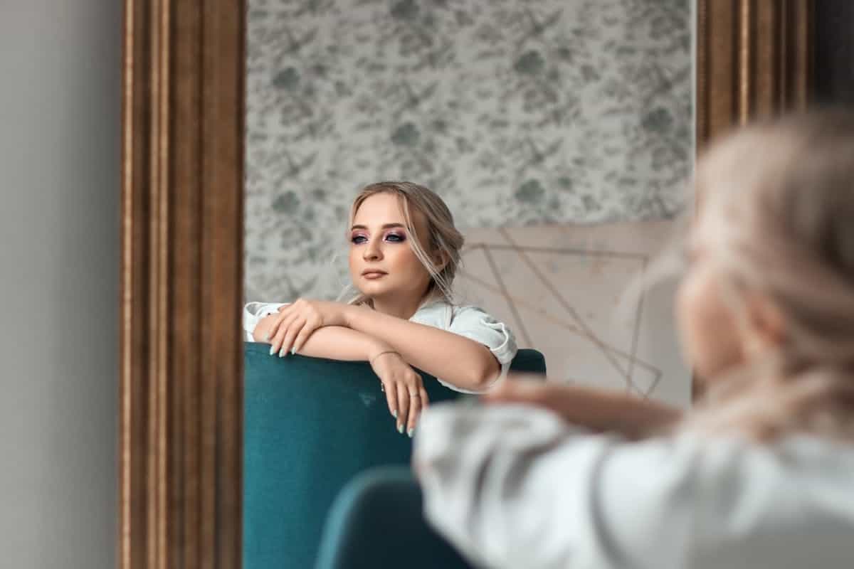 Elegant woman before decorative mirror emphasizing depth cues and diminishing repeated reflections discussed in optics