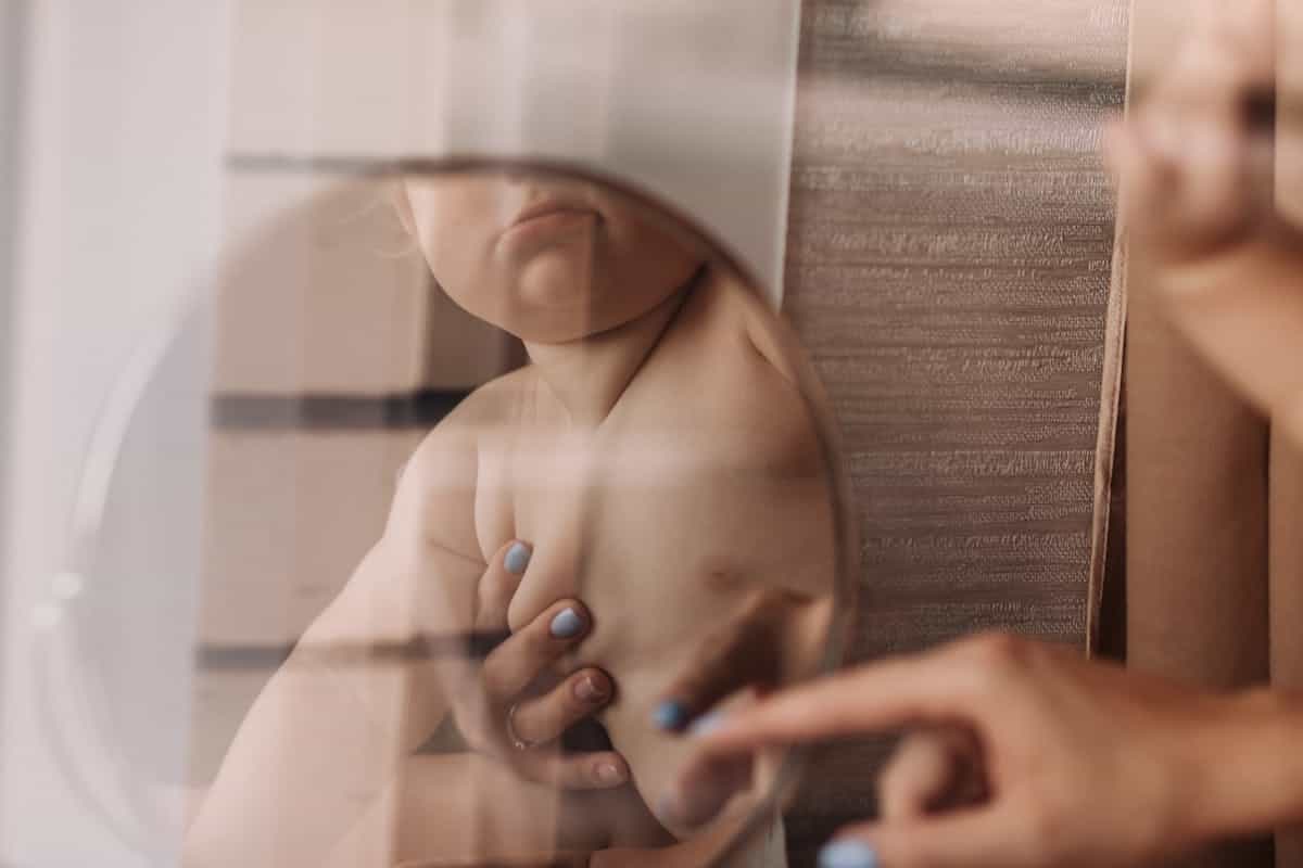 A tender moment of a parent and baby's reflection in a mirror indoors