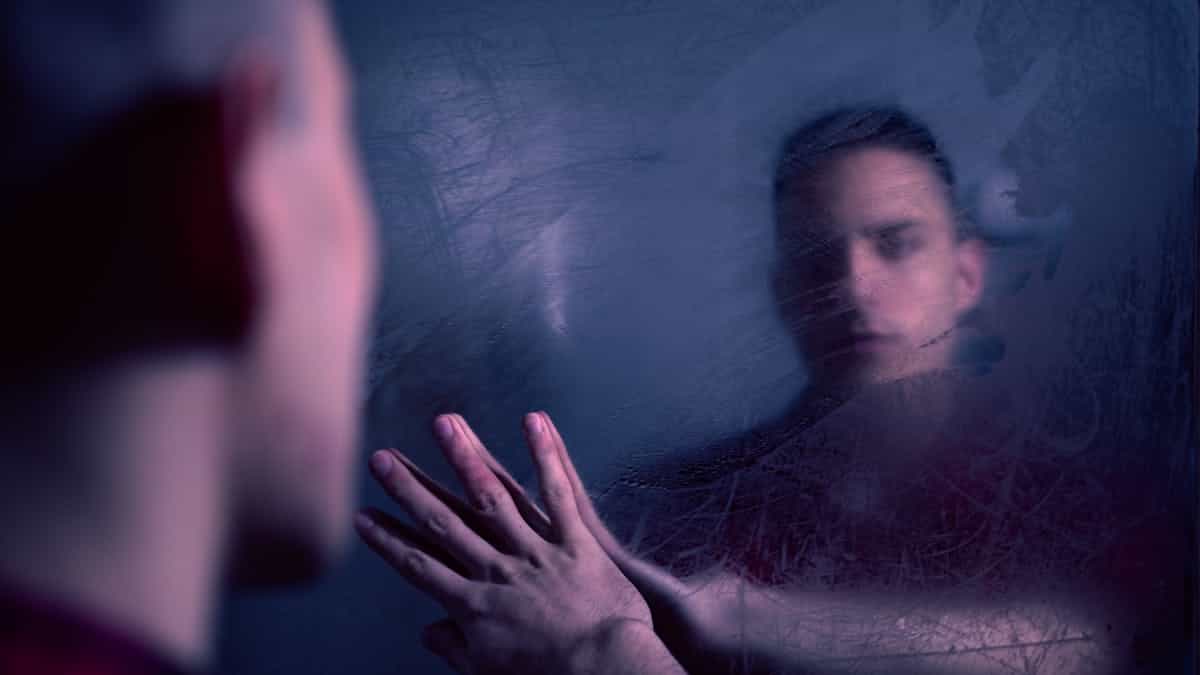 A blurred and reflective portrait of a person touching a foggy mirror capturing a mysterious introspective atmosphere related to foggy mirror dream meaning